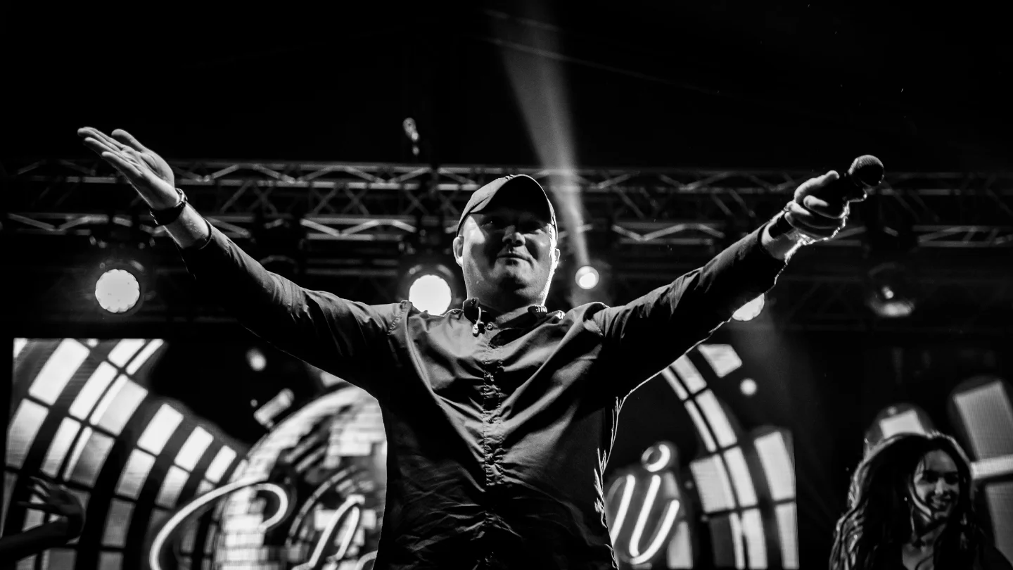 Energiczny wokalista zespołu Stylovi w trakcie dynamicznego występu disco, rozpalający atmosferę na tle tłumu entuzjastycznych fanów.